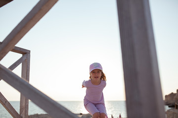 Happy pretty girl walks along the sea coast against the background of the sea, from behind a beautiful landscape