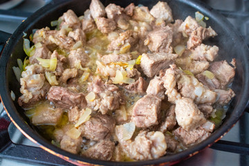 Roasting pieces of meat with onion in a frying pan.