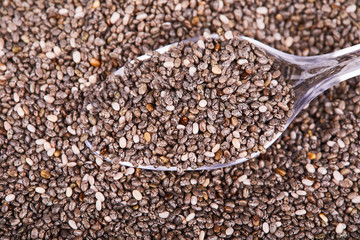 Healthy Chia seeds in transparent glass (plastic) spoon isolated with white background. Top view