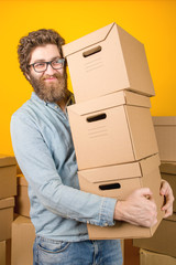 Courier delivers a parcel in three cardboard boxes standing on a yellow background, vertical photo