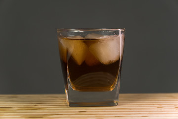 Glass of whiskey on wooden background close up
