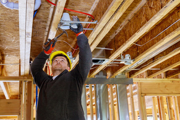 The electrician nailing to the ceiling lamp, installs the lighting lamp