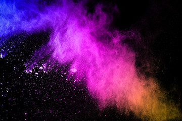 Multi colored dust splash on black background.Painted Holi.Colorful background of pastel powder explosion.