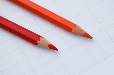 Red and a orange color wood pencil crayon placed beside one another on a white background