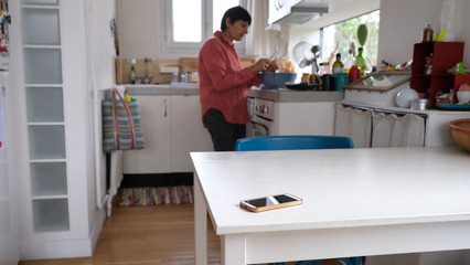 téléphone mobile posé sur une table et dans le fond une personne cuisine