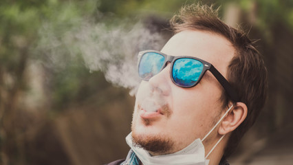 man hipster in glasses smokes a cigarette