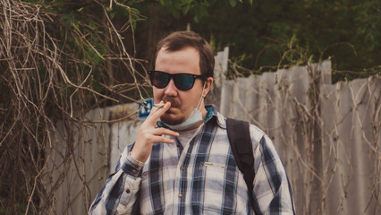 man hipster in glasses smokes a cigarette