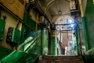 green painted graffiti and sunlit arch leading to the courtyard