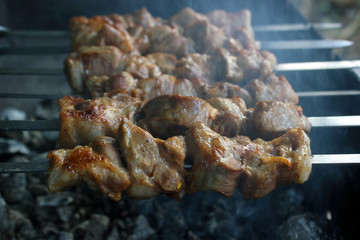 Tasty pork shish kebab on skewers roasting on hot smoky charcoal