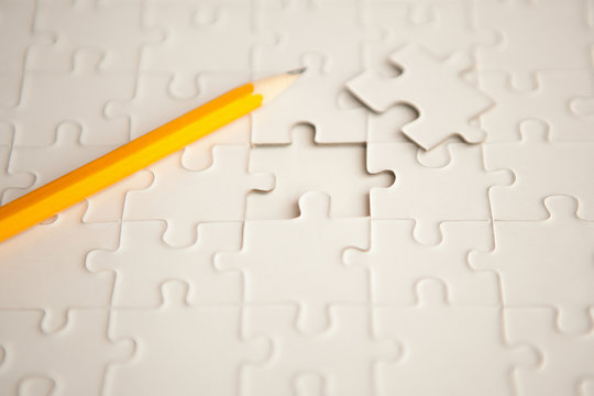yellow pencil, puzzle with missing piece - solution concept. plan white puzzle surface texture with copy space.