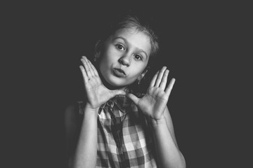 Cute little girl posing on black background. Monochrome photo.