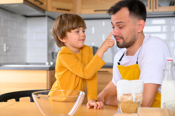Front view father and child in the kitchen having fun while cooking