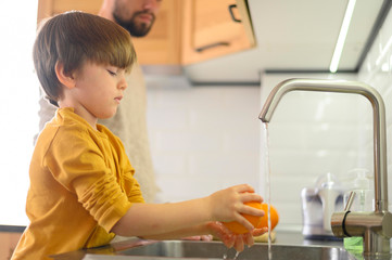 Child washing a lemon in the sink