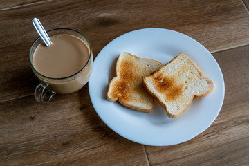 Cup of coffe with milk and two slices of toasted sandwich bread on a white plate. Healthy breakfast with coffee. Free space for text. Side view.