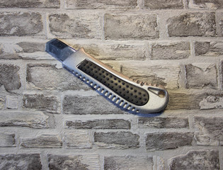 Office knife on a brick background. Background like texture