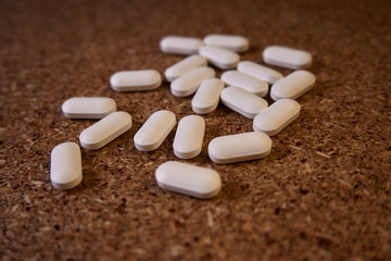 Píldoras blancas regadas sobre aglomerado de madera