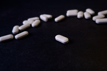 Fototapeta na wymiar píldoras blancas sobre mesa negra