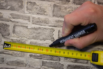 We measure the yellow roll on a brick wall and make marks with a marker for further work..