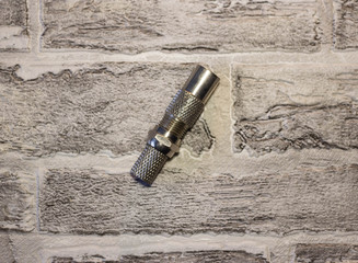 Metal and plastic plug for the antenna in the televisor on the background of a brick wall..