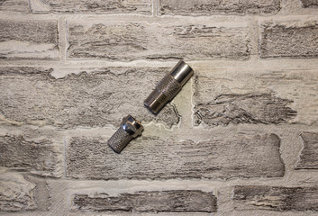 Metal and plastic plug for the antenna in the televisor on the background of a brick wall..