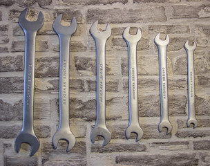 Set of open-end wrenches under the nuts on a brick wall background. .