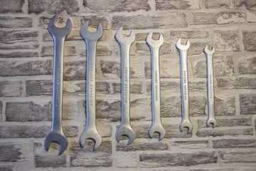 Set of open-end wrenches under the nuts on a brick wall background. .