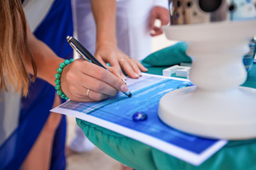 Bride signing wedding marriage certificate with pen on outdoor wedding ceremony 