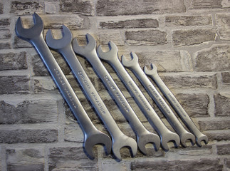 Set of open-end wrenches under the nuts on a brick wall background. .