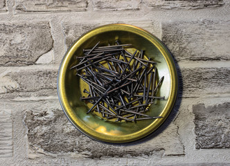Black Nails on a metal stand against a brick wall.