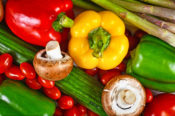 Various fresh raw vegetables like bell pepper, tomatoes, cucumber and mushrooms