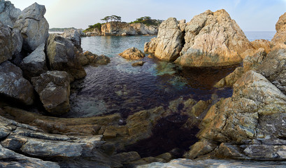 Rocky high island in the ocean. Rocky high island in Orlik Bay in the Sea of Japan. In the foreground are stones and clear water. Far East.
