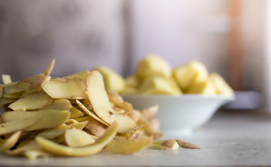 potato peelings whit chopped potatoes in a white bowl light pastel background