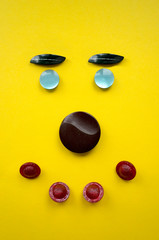 Stylized human face made of buttons on a yellow background