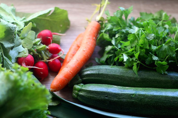 Various vegetables and herbs on a table: leek, lettuce, asparagus, parsley, carrot and radish. Selective focus.