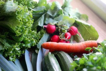 Various vegetables and herbs on a table: leek, lettuce, asparagus, parsley, carrot and radish. Selective focus.