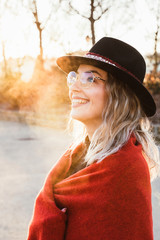 Vertical portrait of beautiful blonde woman on a cold morning outdoors. Cheerful woman smiling on the street with fashion glasses and trendy style. Beautiful woman sightseeing on winter season.