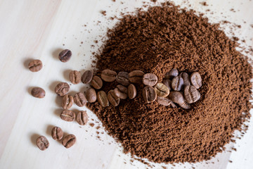 Top view of coffee beans and ground coffee on wooden background, roasted coffee volcano like anthill