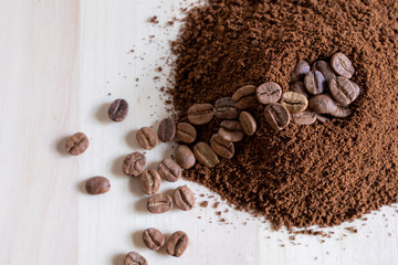Top view of coffee beans and ground coffee on wooden background, roasted coffee volcano like anthill