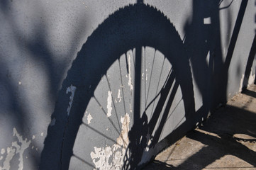 Detailed shadow of a bicycle wheel on the grey vintage wall. Bike wheel silhouette.