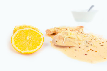 chicken fillets in cream sauce with lemon and spices, on a white background. In the bottom bowl with sauce.