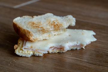 Bread tossed to the floor. Thrown into the trash food. Half Eaten Sandwich thrown on the floor. Discarded Sandwich. Close-up side view. Concept.