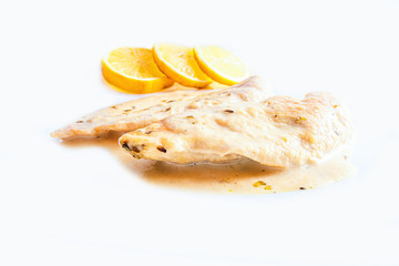 chicken fillets in cream sauce with lemon and spices, on a white background.