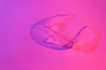 Protective transparent glasses in neon pink light.