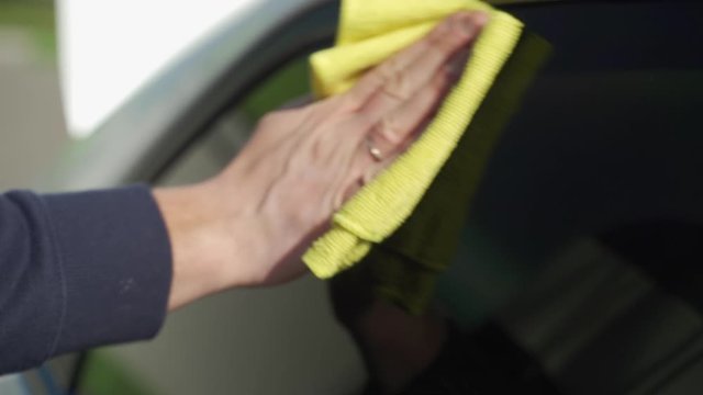 Auto care service staff cleaning car window glass with microfiber cloth