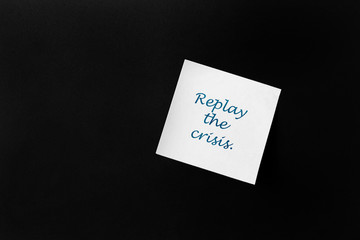 On a black background, a white sticker with the inscription: "Replay the crisis".The concept of anti-crisis development.