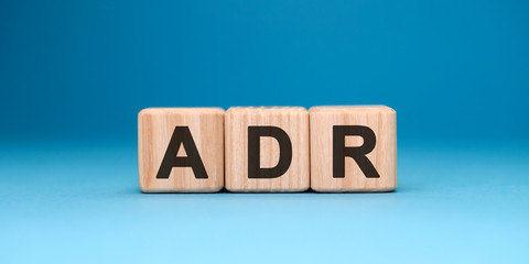 ADR word cube on a blue background. Business concept.