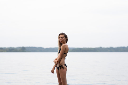 Young female wearing a bikini, lake in the background, looking at camera.