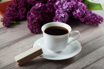 cup of coffee and lilac on table