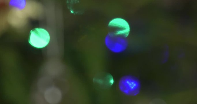 A close-up of the decorated Christmas tree with moving focus to the background. Blurred mysterious image of Christmas tree decorations.