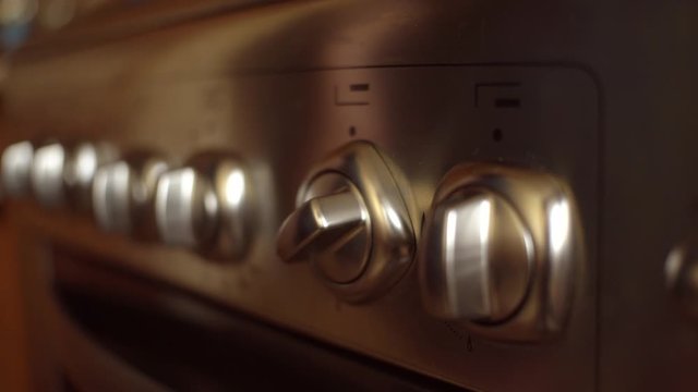 hand twist knob on modern gas stove. Woman turn temperature on oven button.